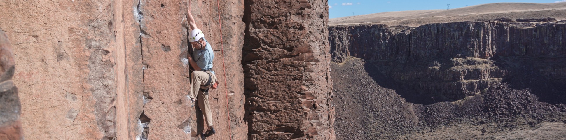 Climber ascending on a steep rock wall in a valley