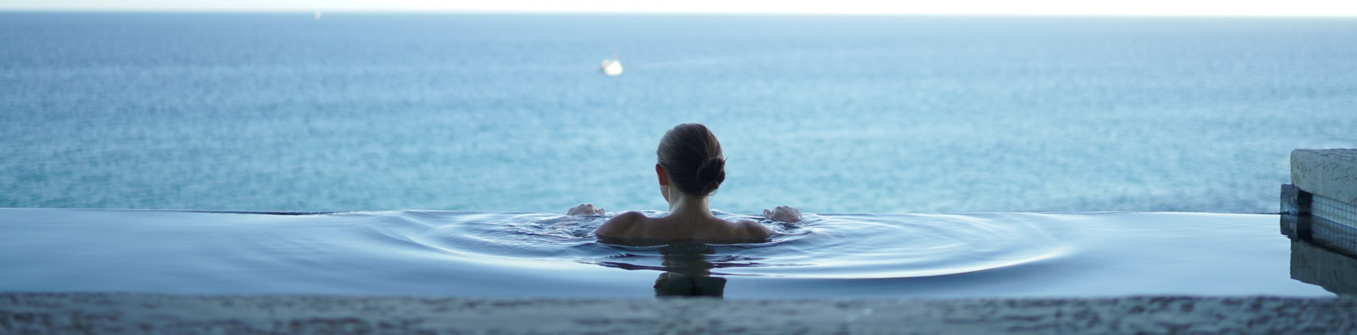 Lady in a swimming pool with an ocean behind, Wellness Tours