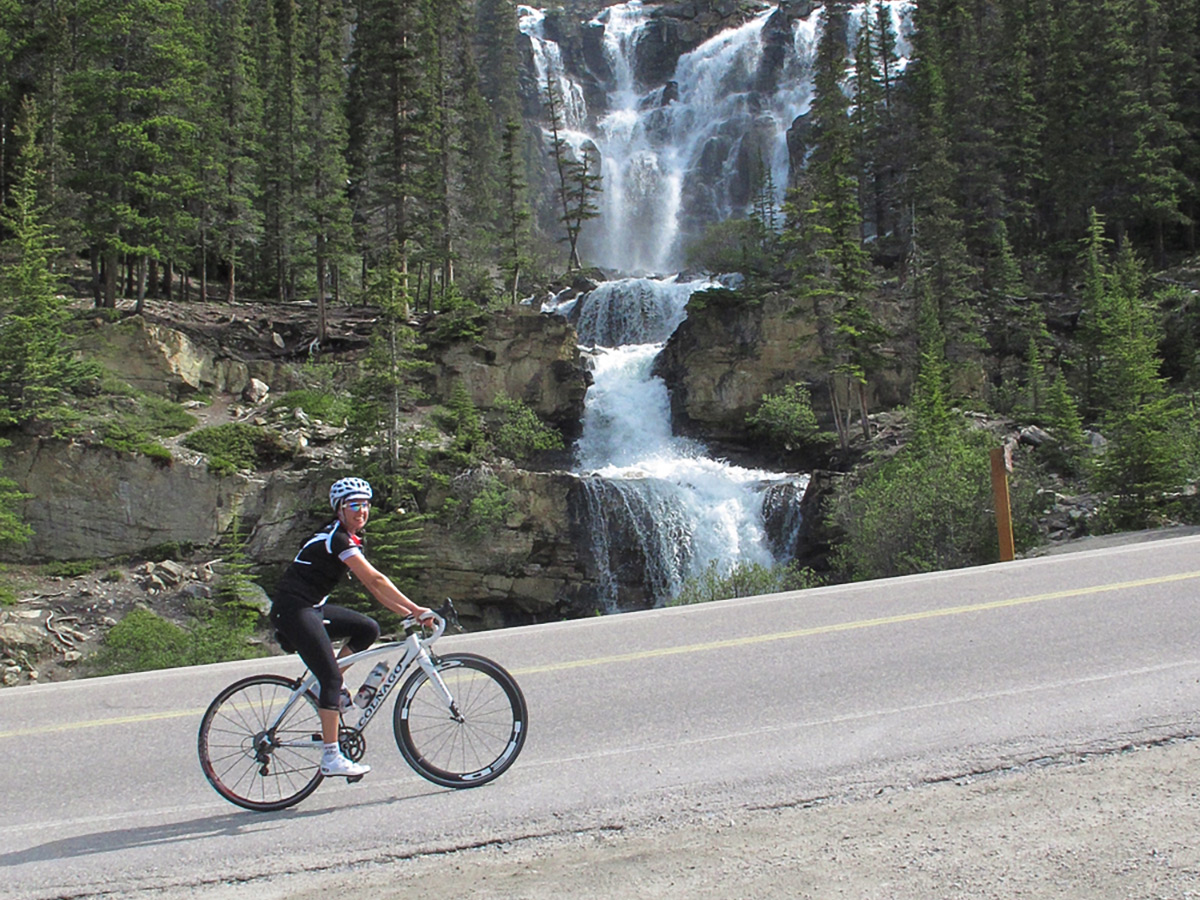 Biker riding near waterfall on guided cycling tour from Jasper to Banff in Canada