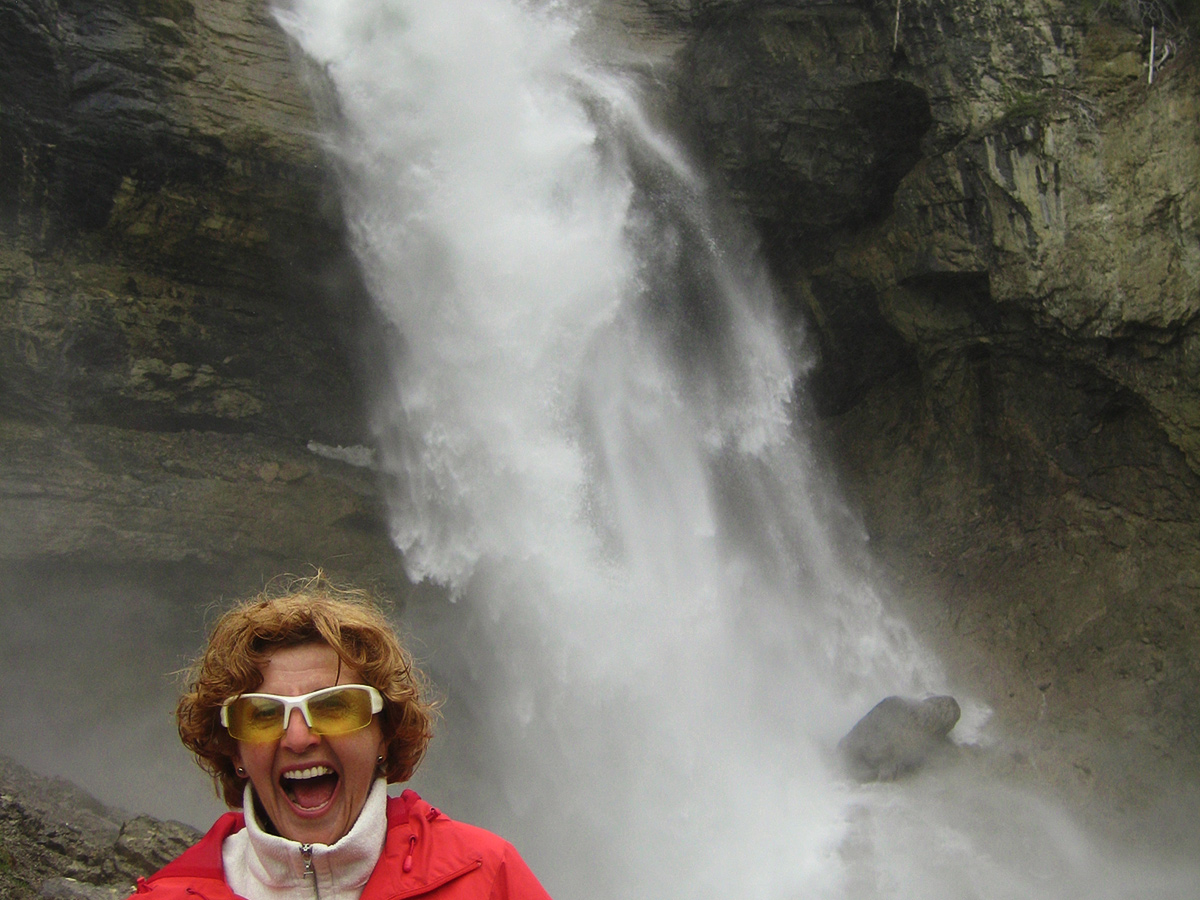 Happy biker posing near waterfall on guided cycling tour from Jasper to Banff in Canada