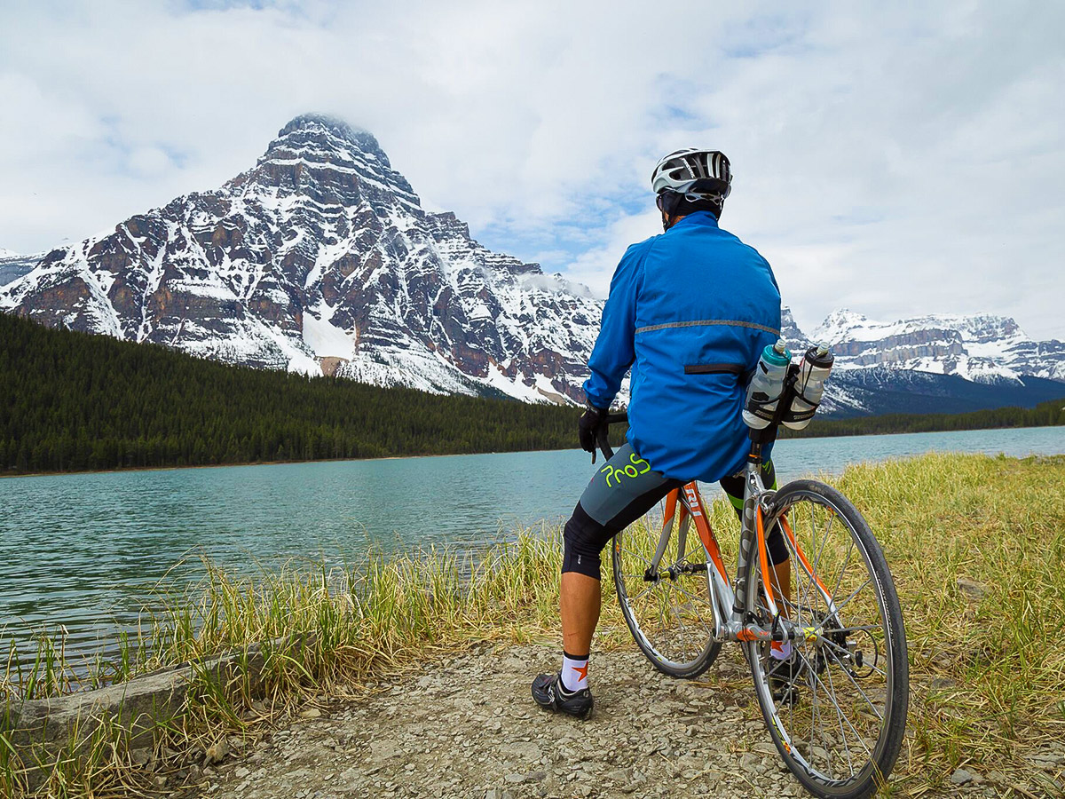 Biker looking at beautiful lake on guided cycling tour from Jasper to Banff in Canada