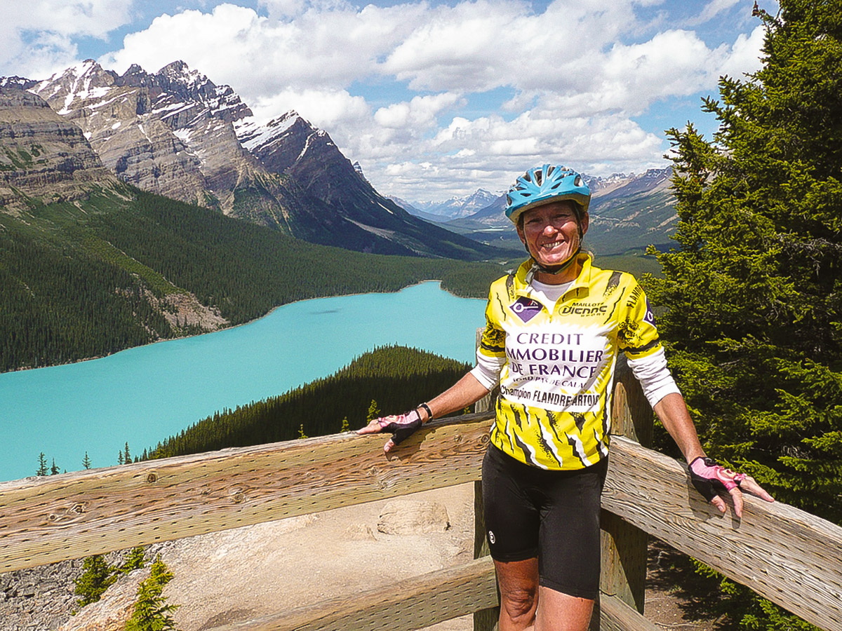 Biker posing near turquoise lake on guided cycling tour from Jasper to Banff in Canada