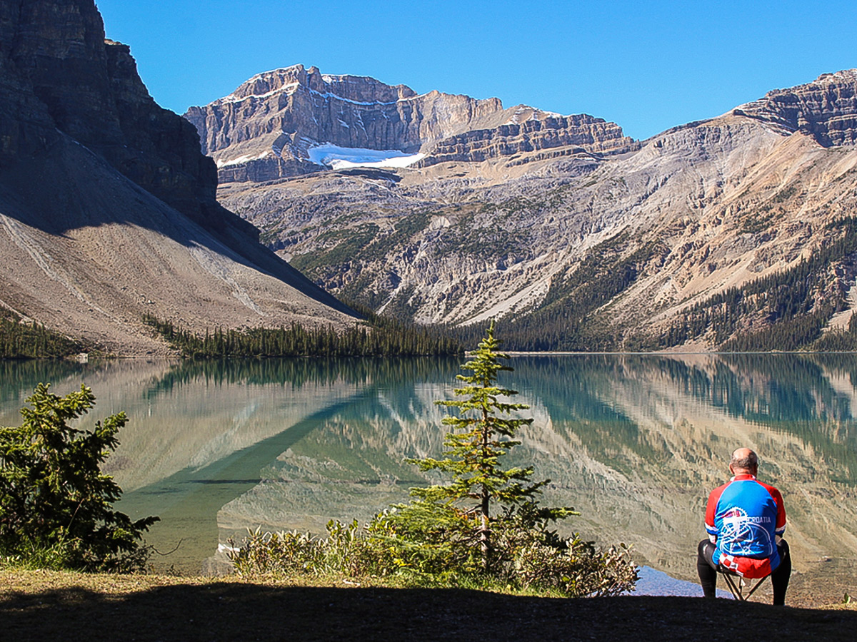 Biker resting near beautiful lake on guided cycling tour from Jasper to Banff in Canada