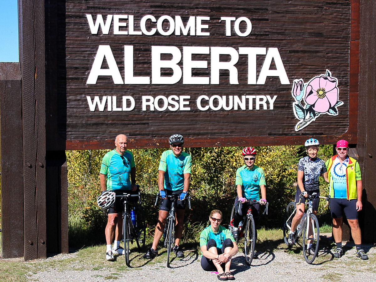 Bikers near Alberta sign on guided cycling tour from Jasper to Banff in Canada