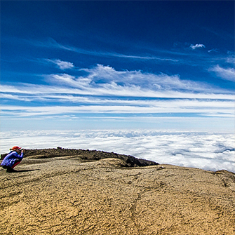 Hiker above the clouds on Kilimanjaro trek on Lemosho Route in Tanzania