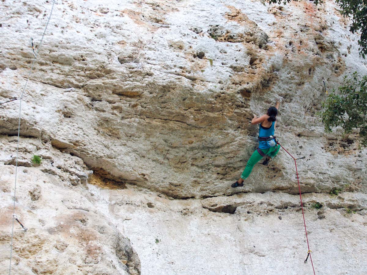 Woman climbing up on rock climbing tour in Finale Ligure