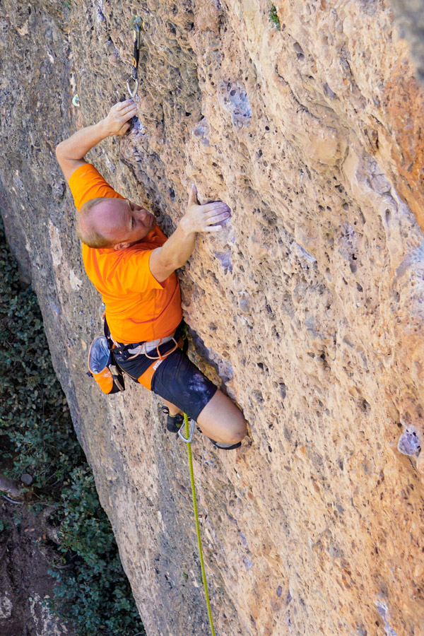 Rock climber ascending on crag on rock climbing tour in Margalef, Spain