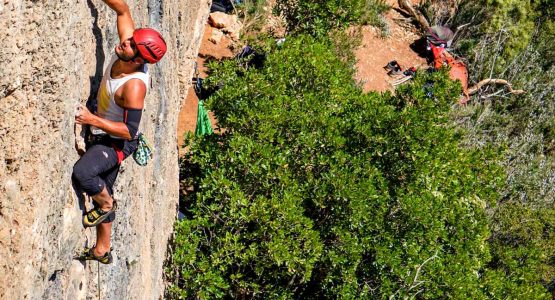 Climber on vertical rock wall on rock climbing tour in Margalef, Spain