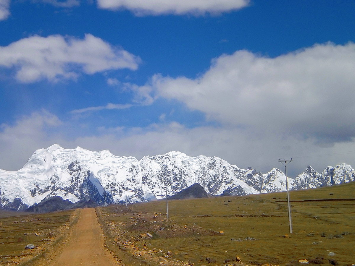 Dirt road heading towards snow covered mountains in the distance