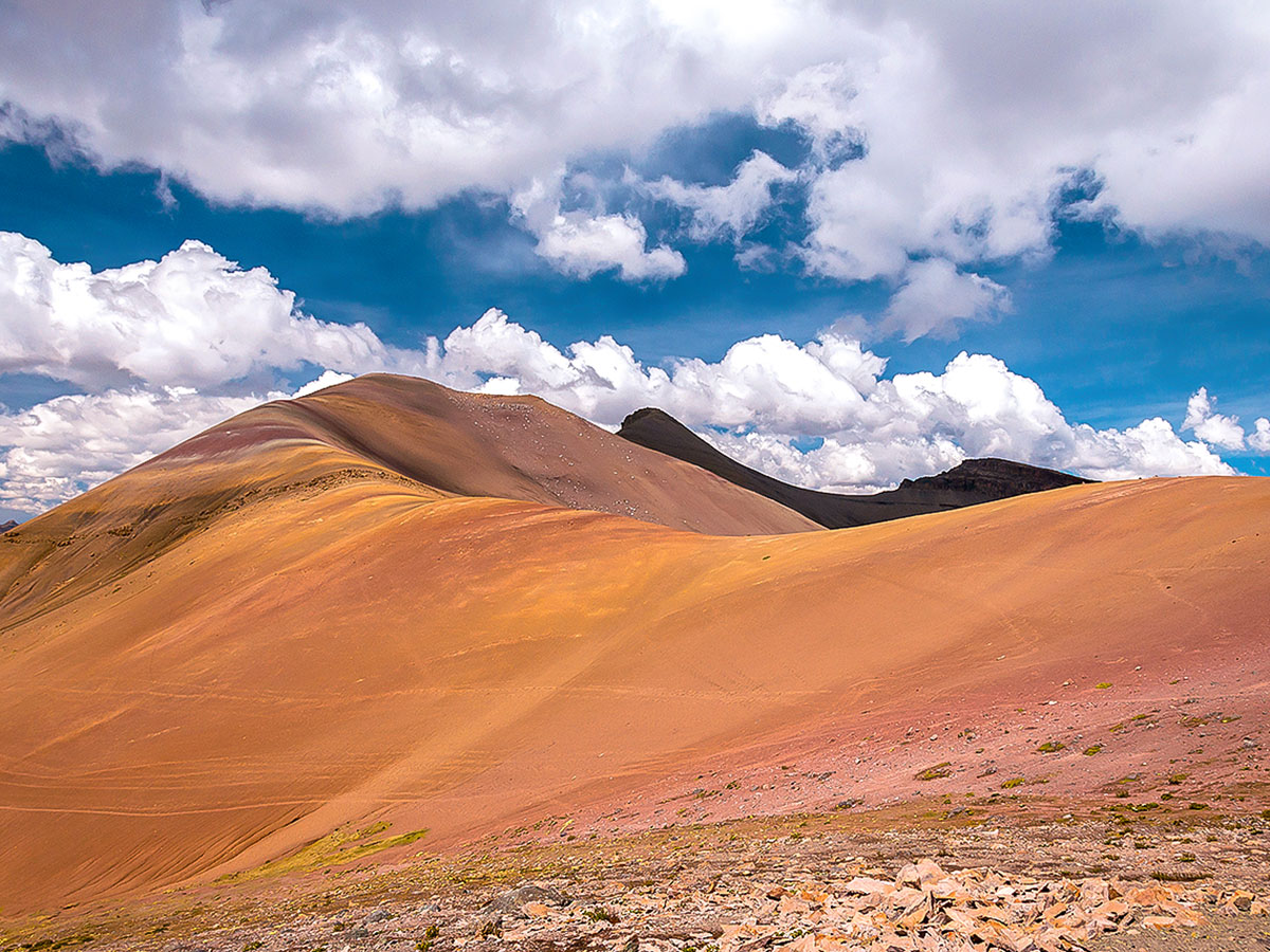 Long ridge under a blue, partly cloudy sky on the striped Rainbow Mountains of Peru