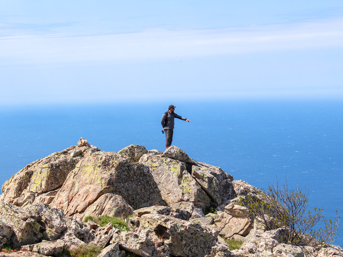 Hiker on the mountain in front of Mediterranean Sea on Corte Calvi Guided Trek in Corsica