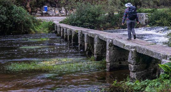 Lone hiker crossing the bridge on Camino de Santiago Portuguese Way