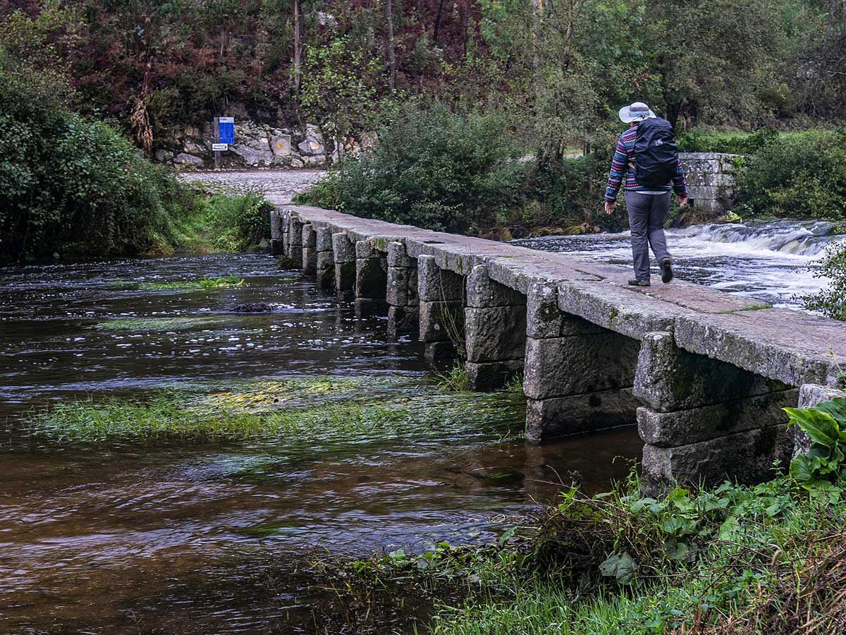 Lone hiker crossing the bridge on Camino de Santiago Portuguese Way