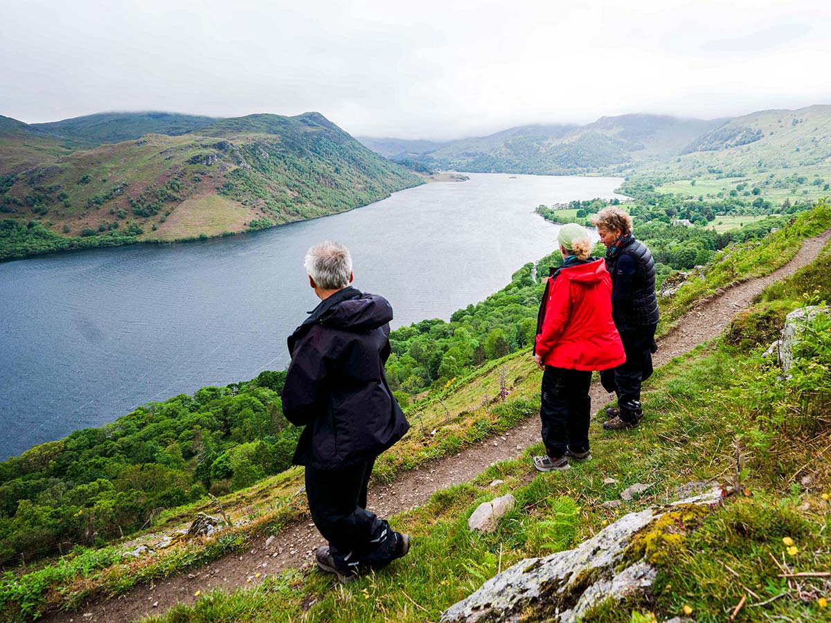 Three hikers looking at the lake on Northumberland and the Lake District walking tour in England UK