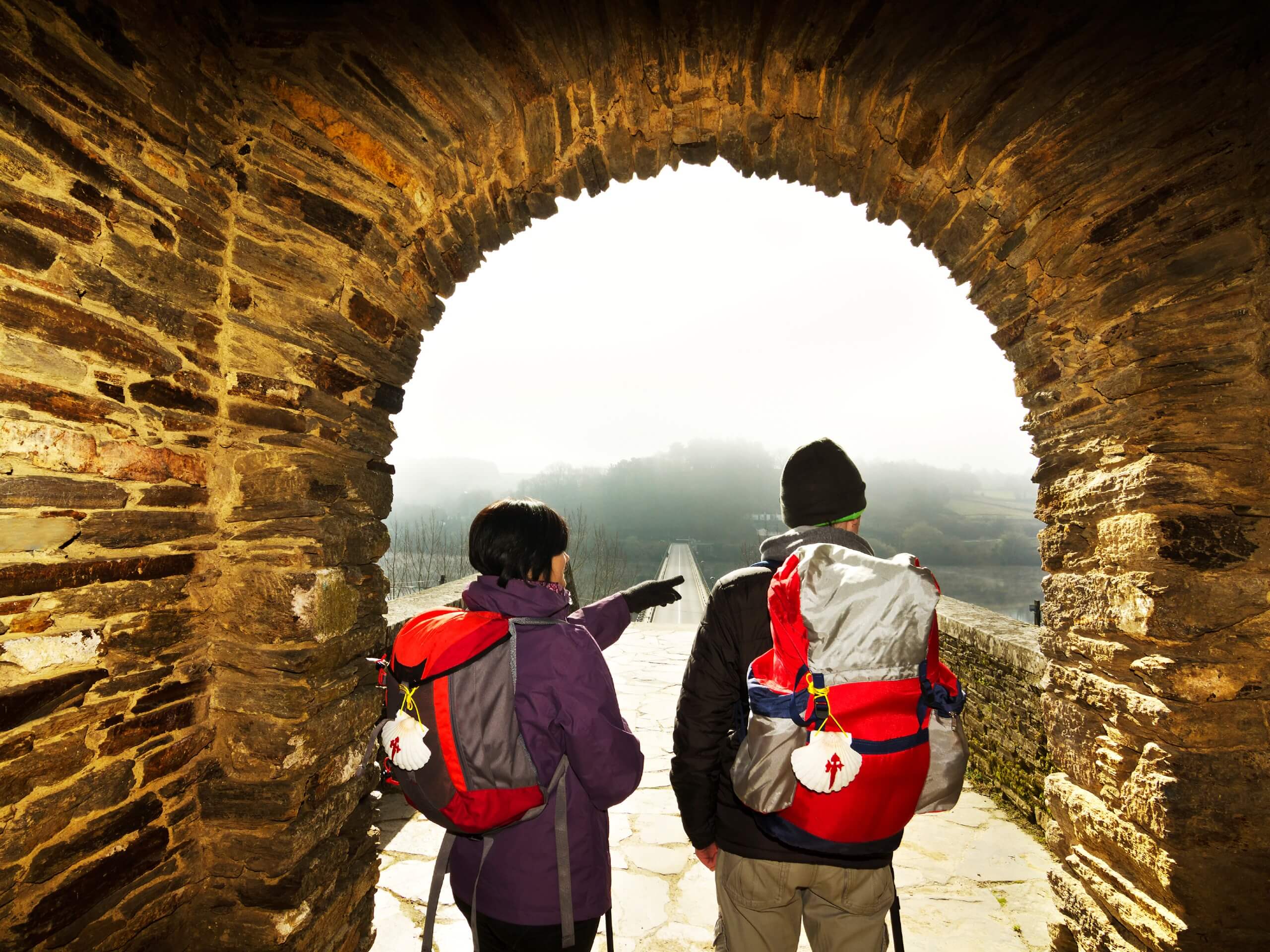 Couple standing in the arch on Camino de Santiago route