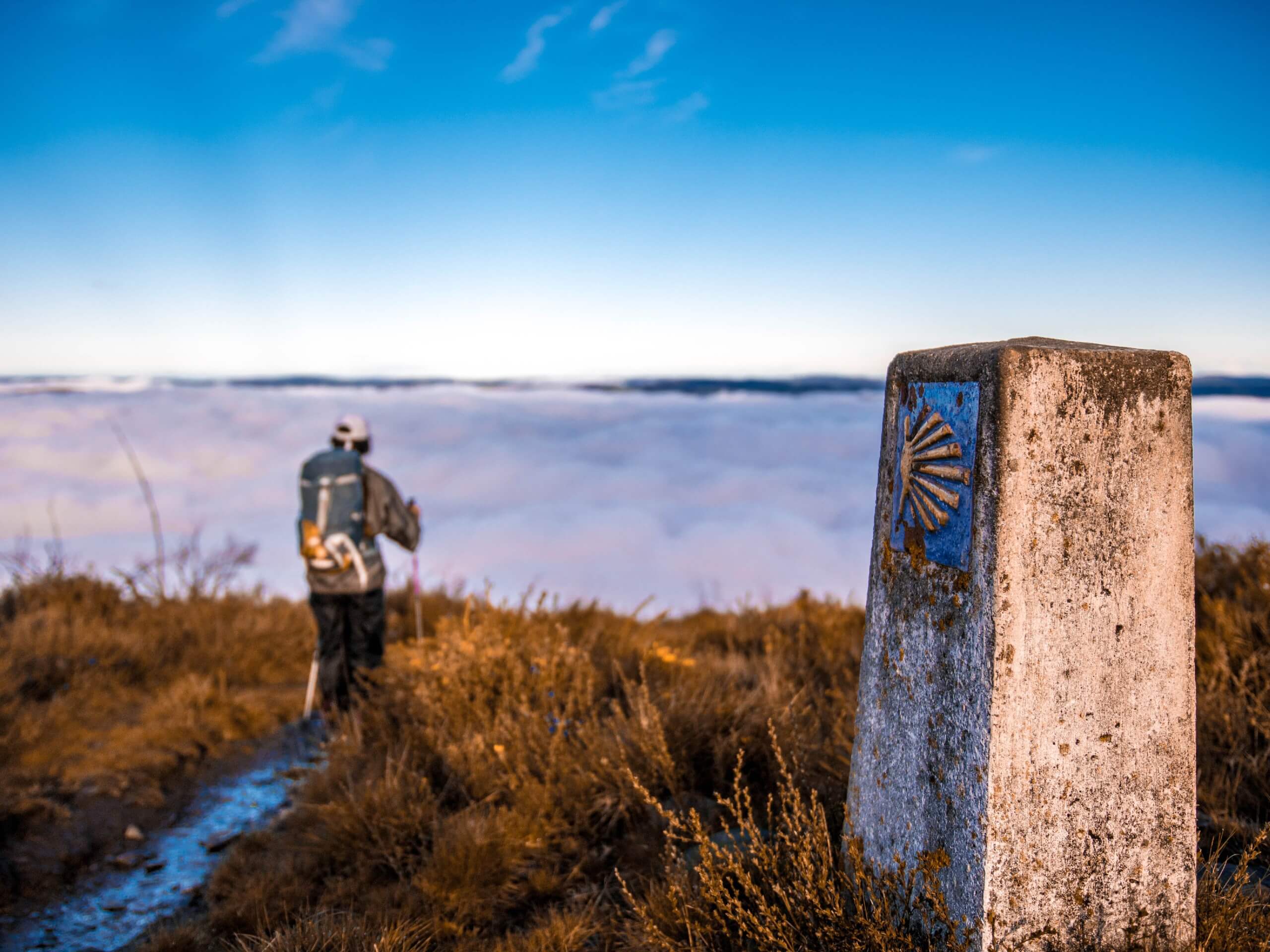 Hiker walking above the clouds on Camino de Santiago route