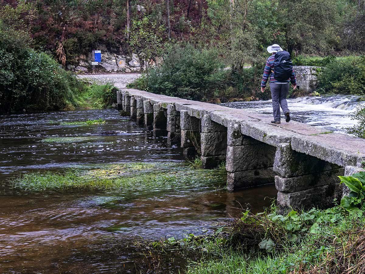 Lone hiker crossing the bridge on Camino de Santiago Portuguese Way in Spain