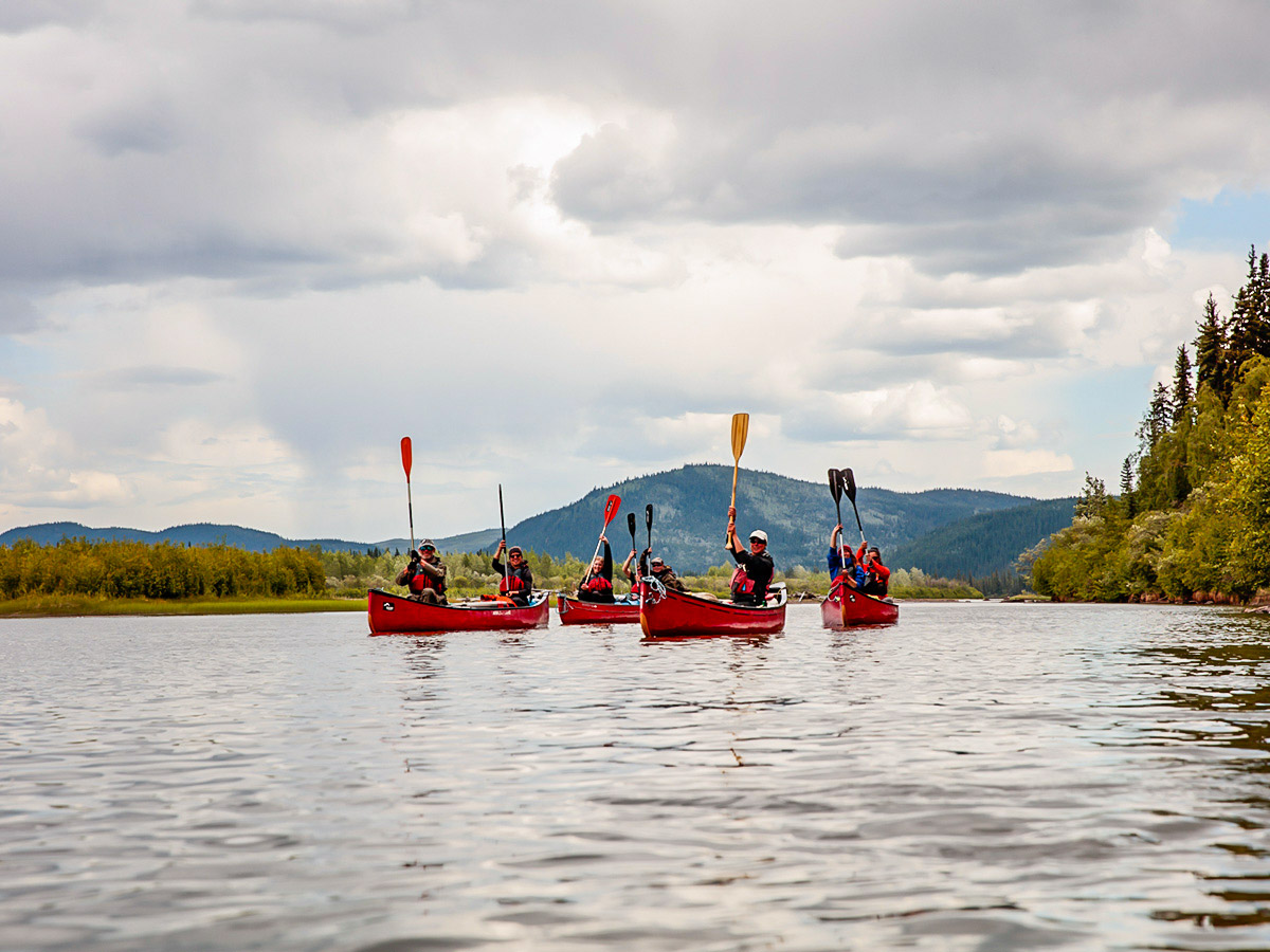 Group posing with the paddles up on Yukon River Canoeing Tour with a guide