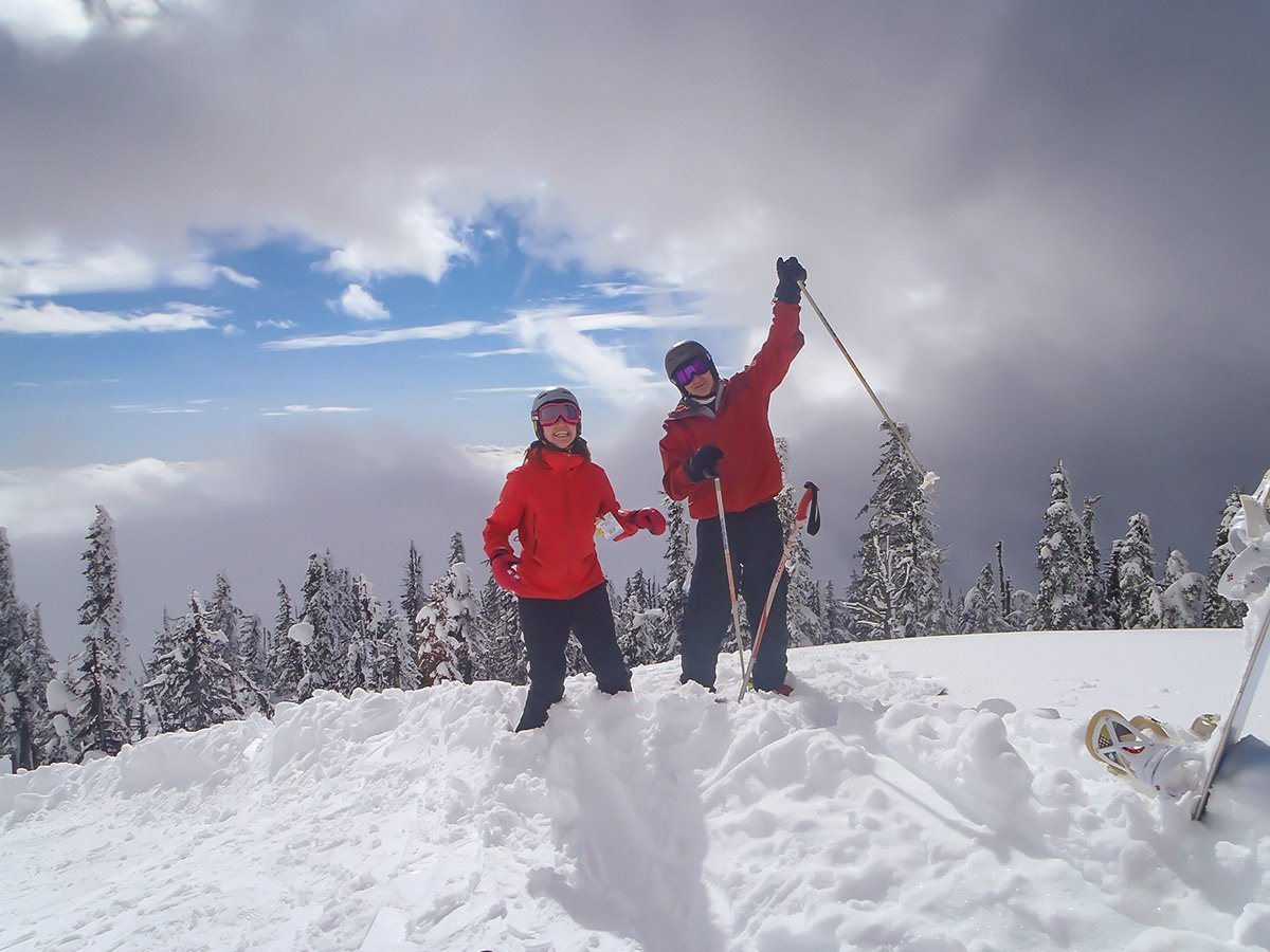 Two skiers dressed in red posing on a mountain