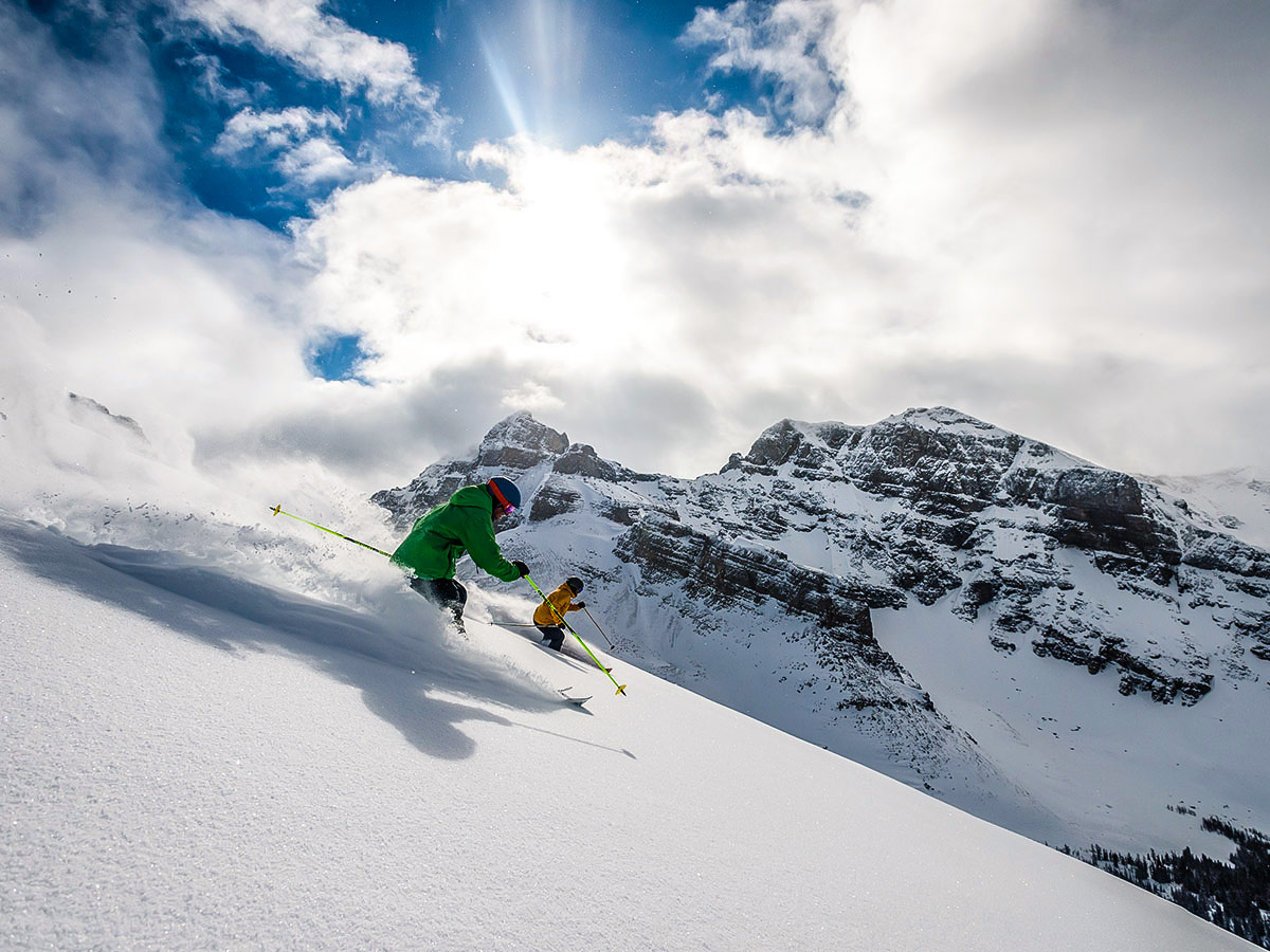 Powdery snow two skiers and mountain views, as seen on a guided skiing tour in British Columbia