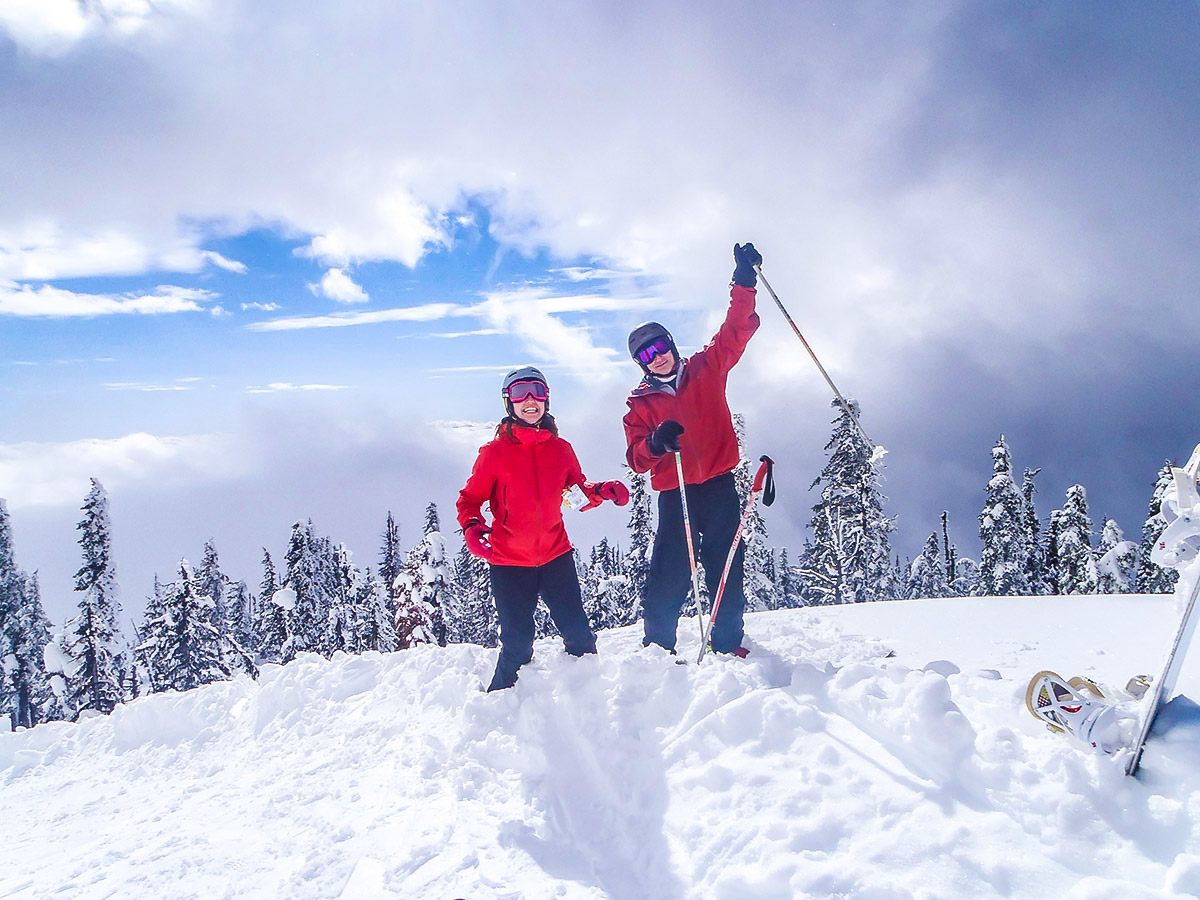 Snowy mountains and two skiers on the British Columbia skiing tour with a guide