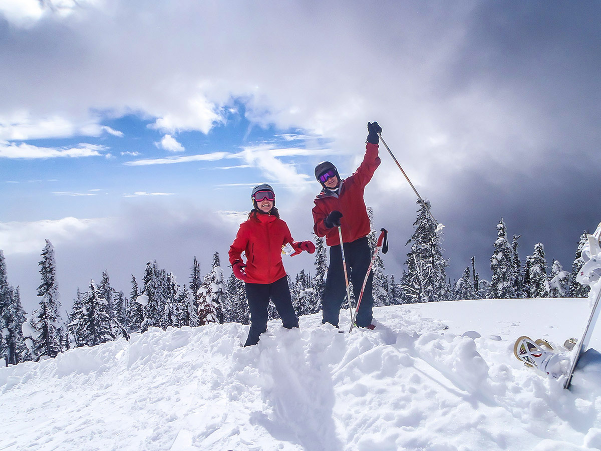 Two skiers posing in front of the beautiful mountain view in one of the British Columbias ski resorts