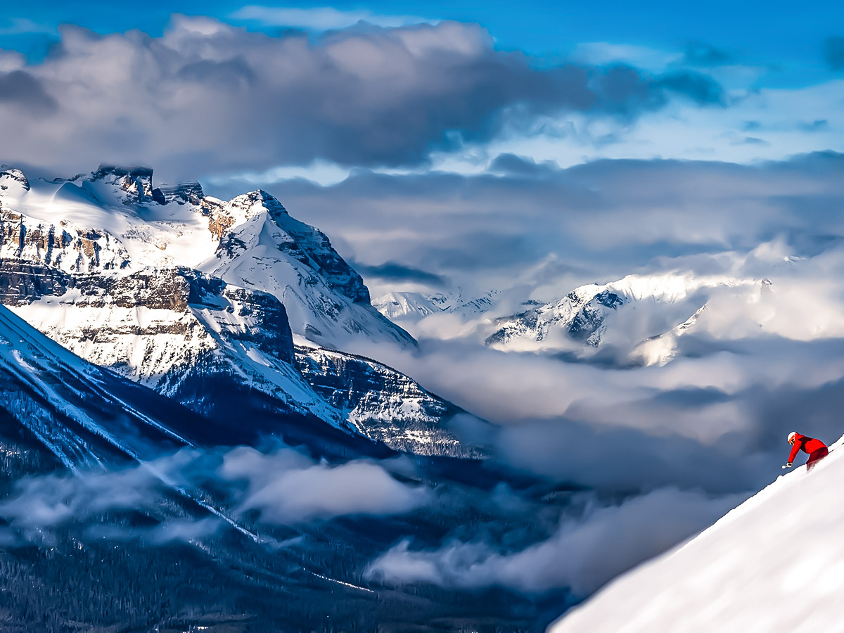 Skier in front of mountain panorama on guided ski tour along the Powder Highway