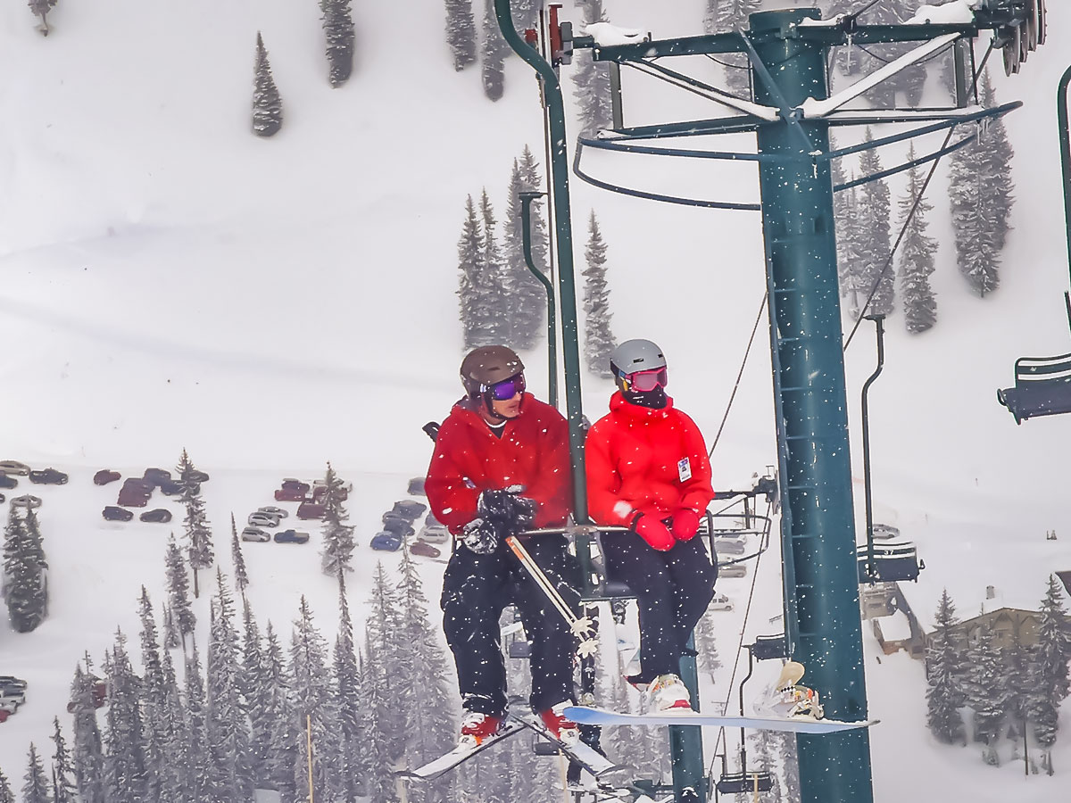 Two skiers dressed in red ascending the mountain