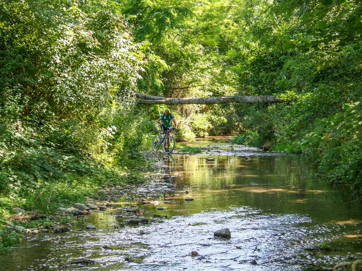 Biker crossing the river in Val dOrcia Tuscany