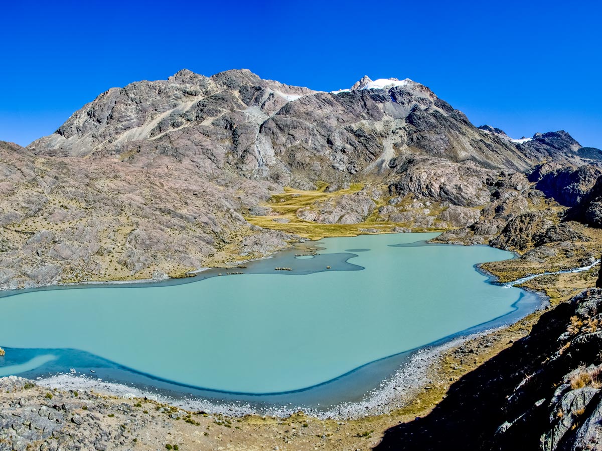 Panoramic view of the hikers observing the lake and the mountains from the above on Apolobamba Trek (image by V.Kronental)