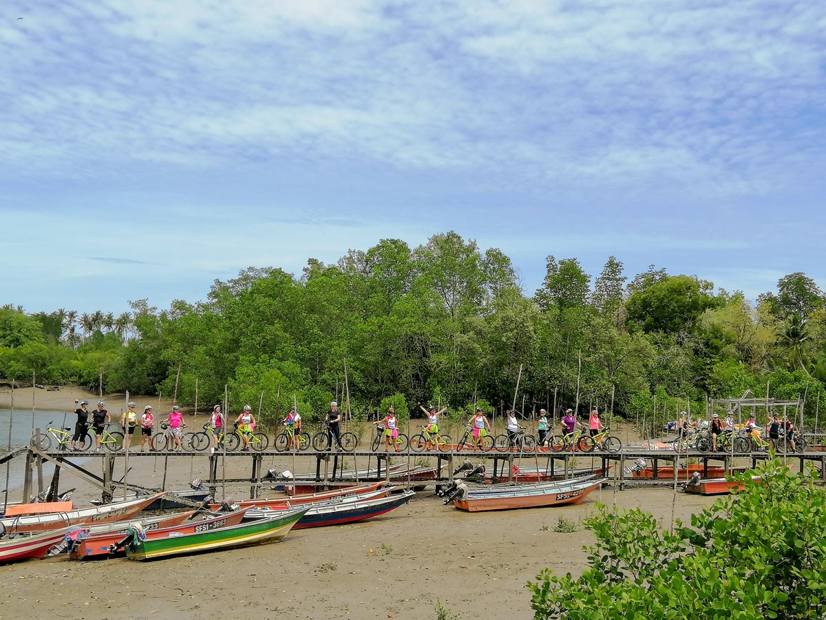 Bikers pose on boat dock along Malaysia Borneo bike ride