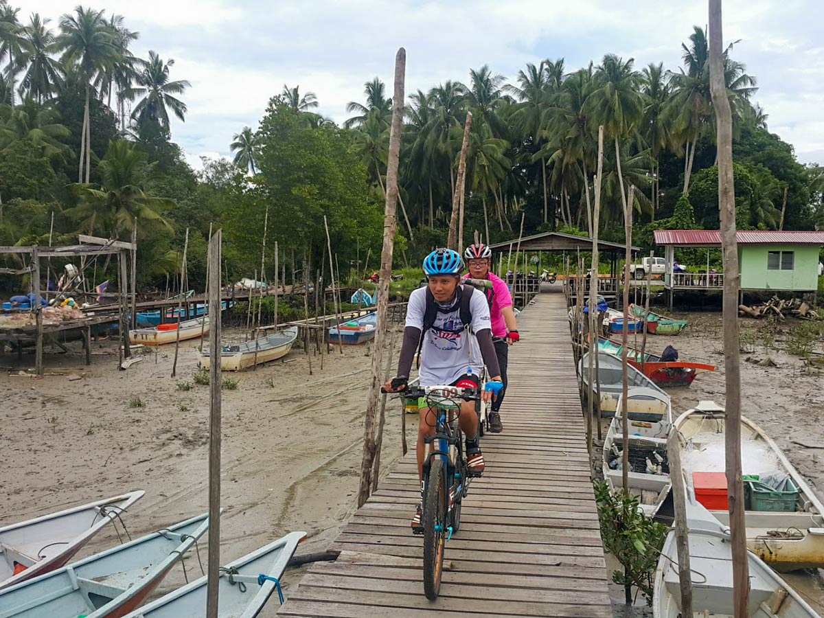 Cycling through fishing village along Malaysia Borneo bike ride