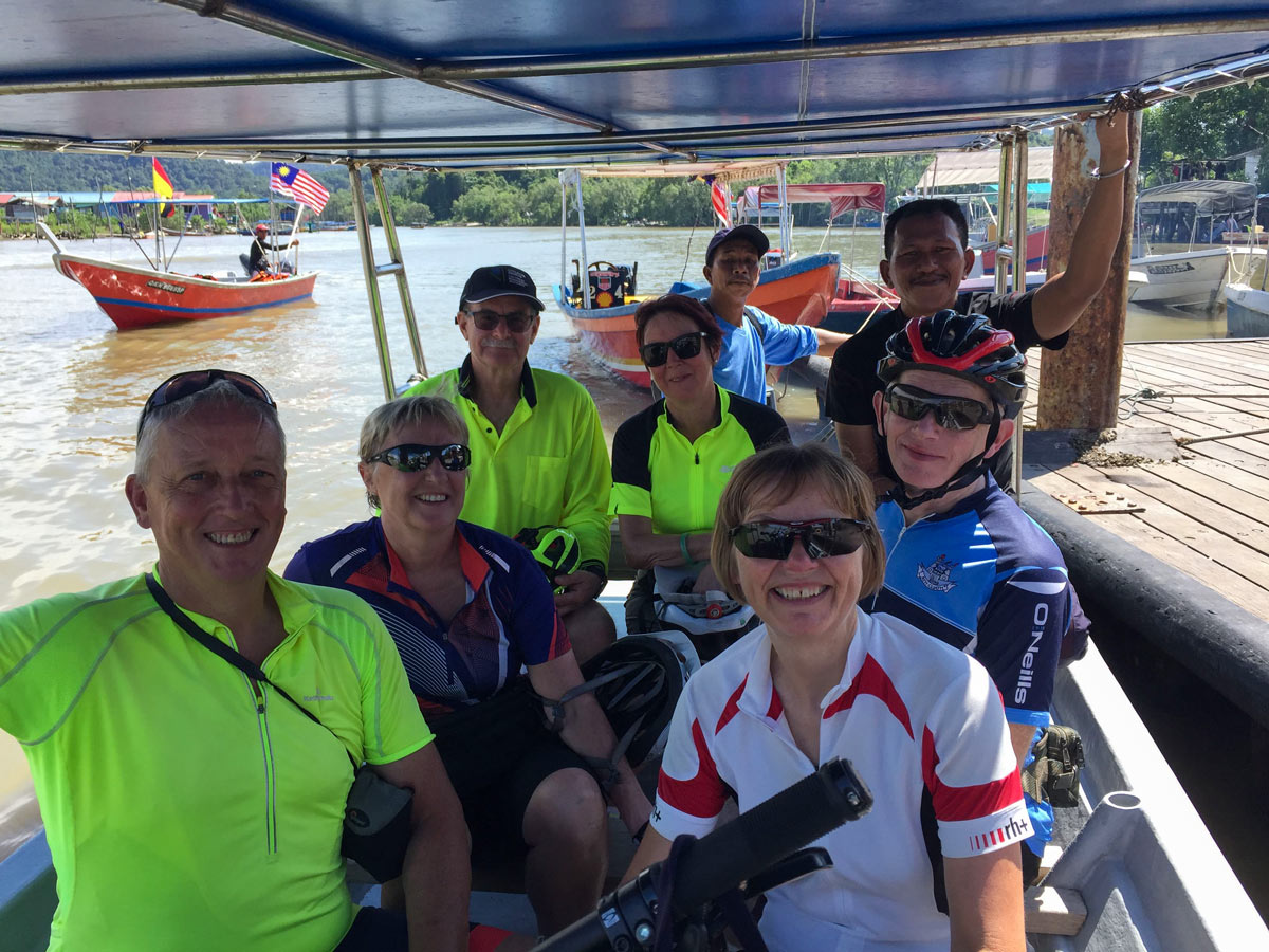 Cycling group on boat ride along Borneo Wildlife Bike Safari tour Malaysia