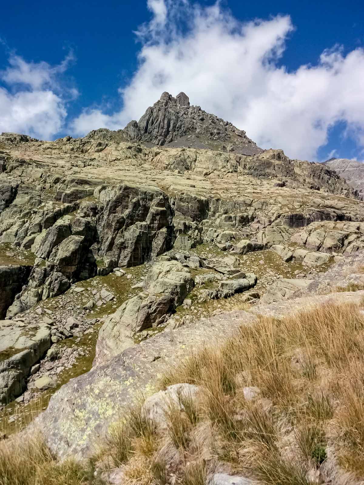 Standing below high mountain peak hiking along Neolithic tour France