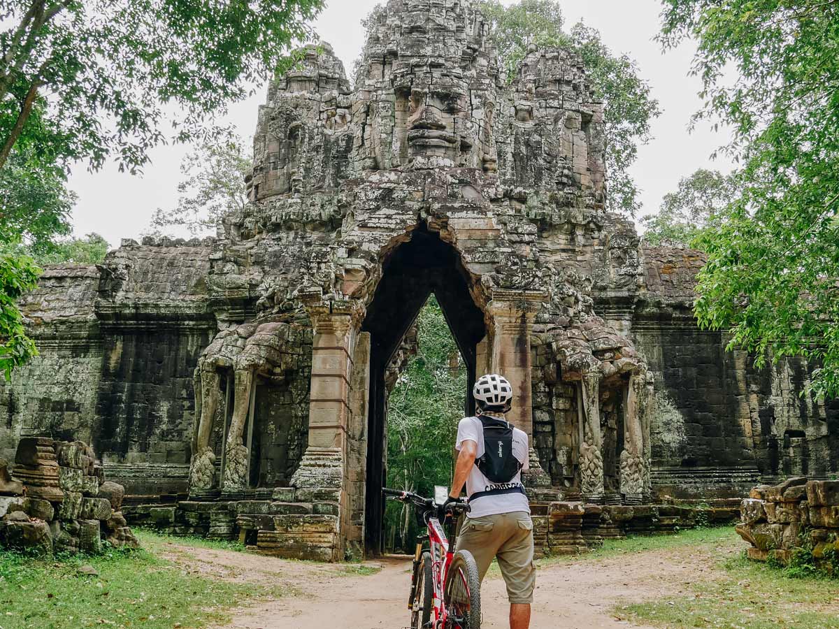 Cyclist posing in Angkor Wat with a bike
