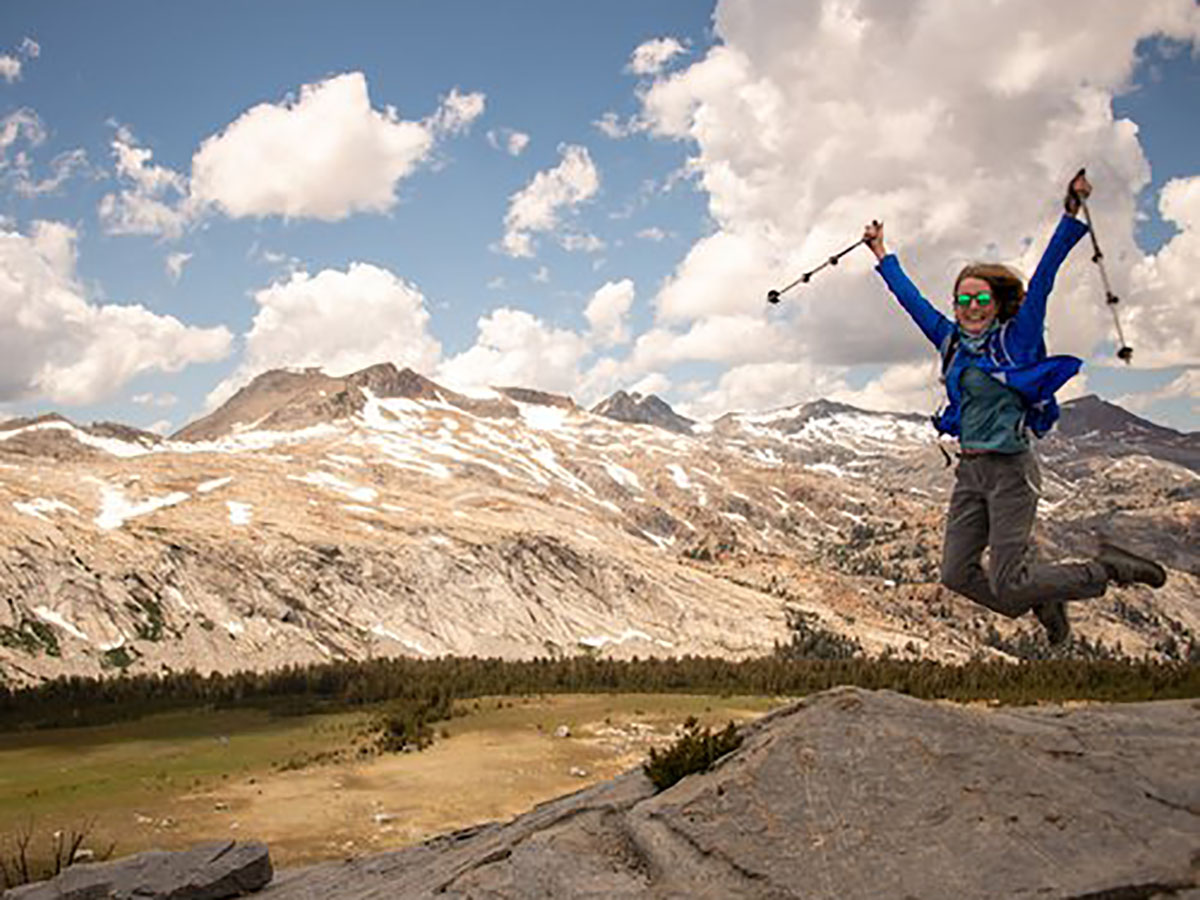 Hiker with hiking poles jumping in Yosemites