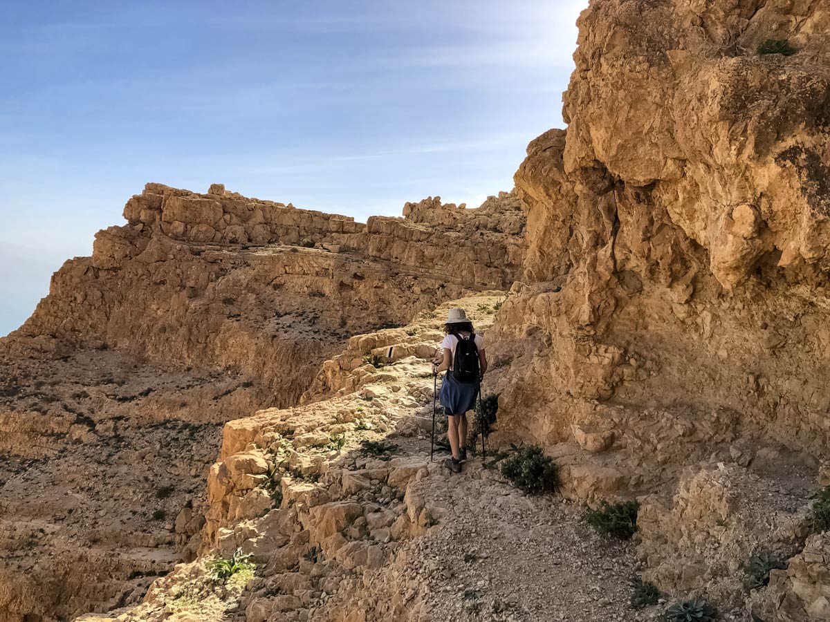 Hiker traverses rock cliff path hiking near Dead Sea in Israel trekking