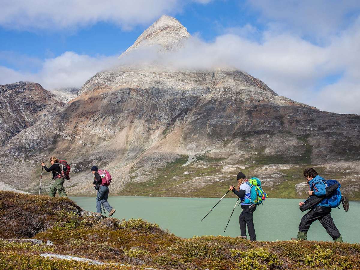 Four hikers hiking along the shore in Greenland