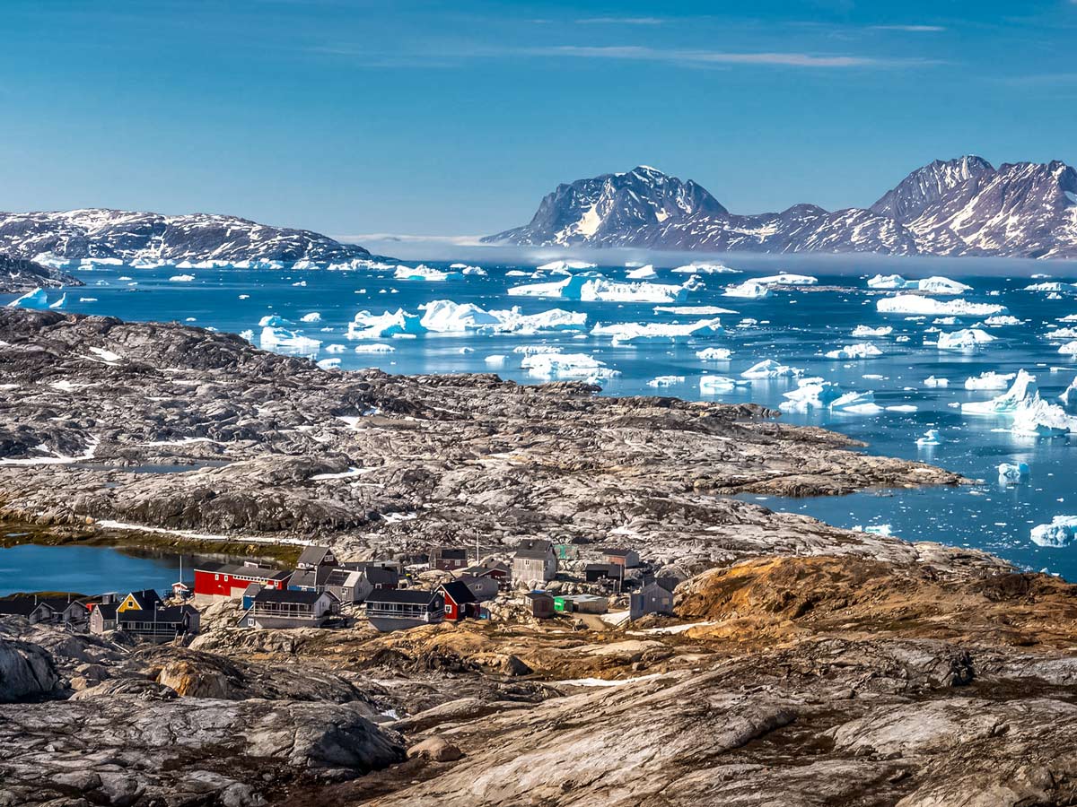 Remote Greenland village iceburgs floating down the channel seen along hiking tour