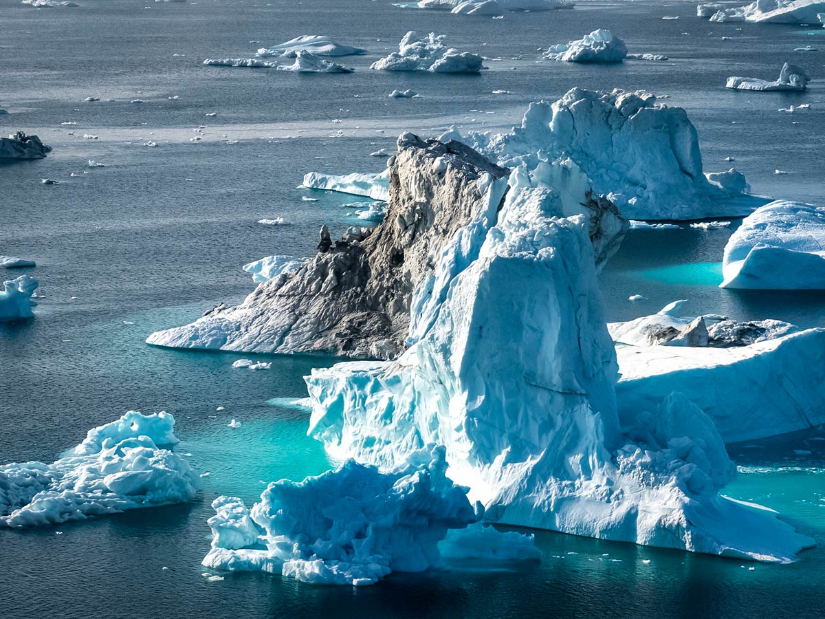 Massive iceburgs floating in the sea waters of Greenland seen along hiking adventure tour