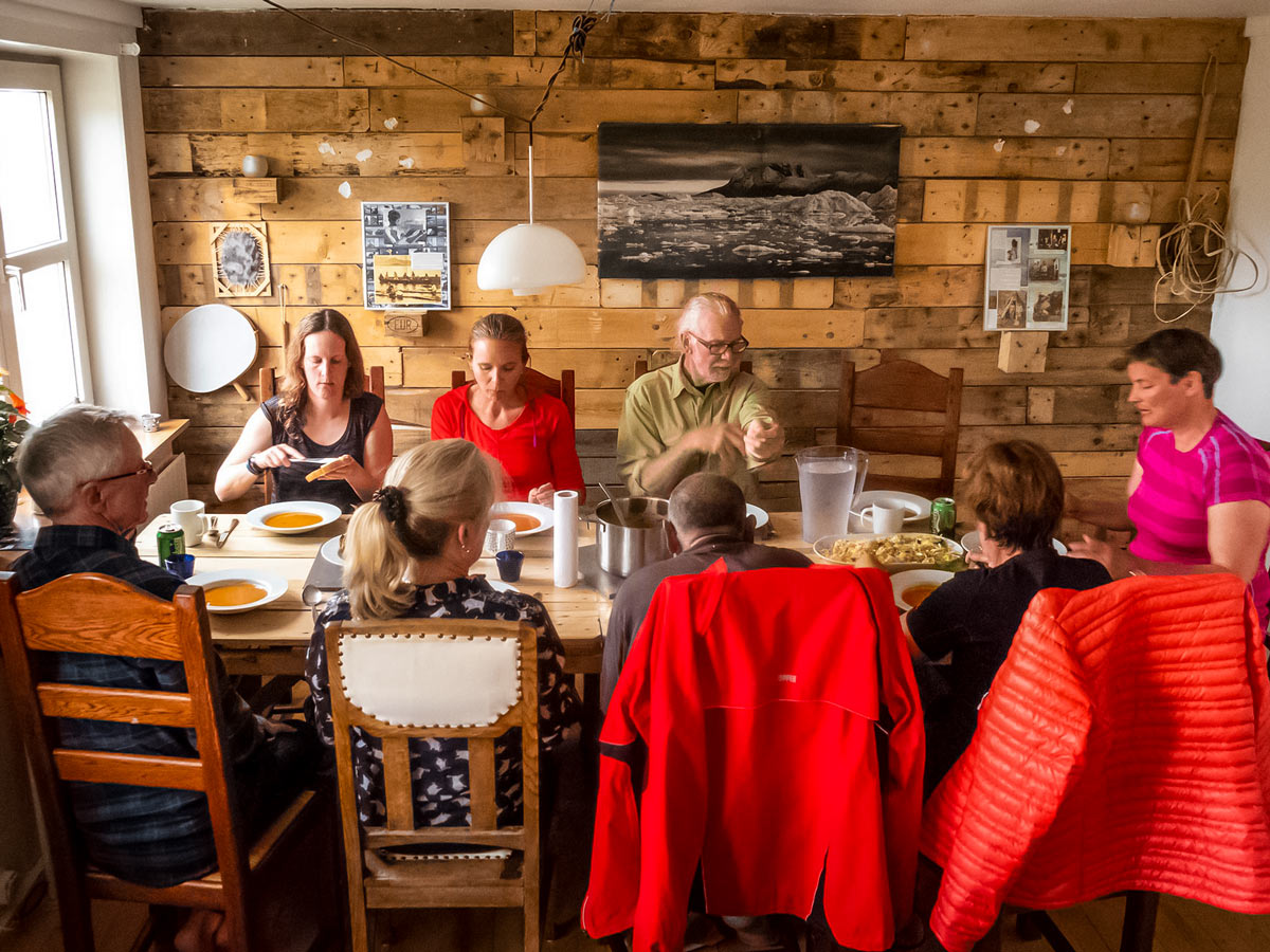 Hiking tour group enjoys a meal together in Greenland cabin house