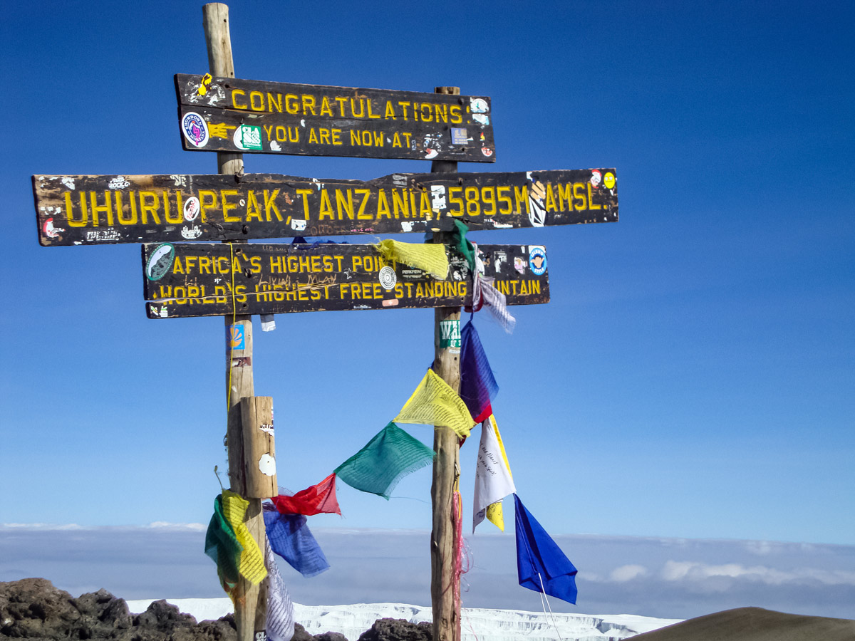 Uhuru Peak sign flags Lemosho trail hike Mount Kilimanjaro Tanzania