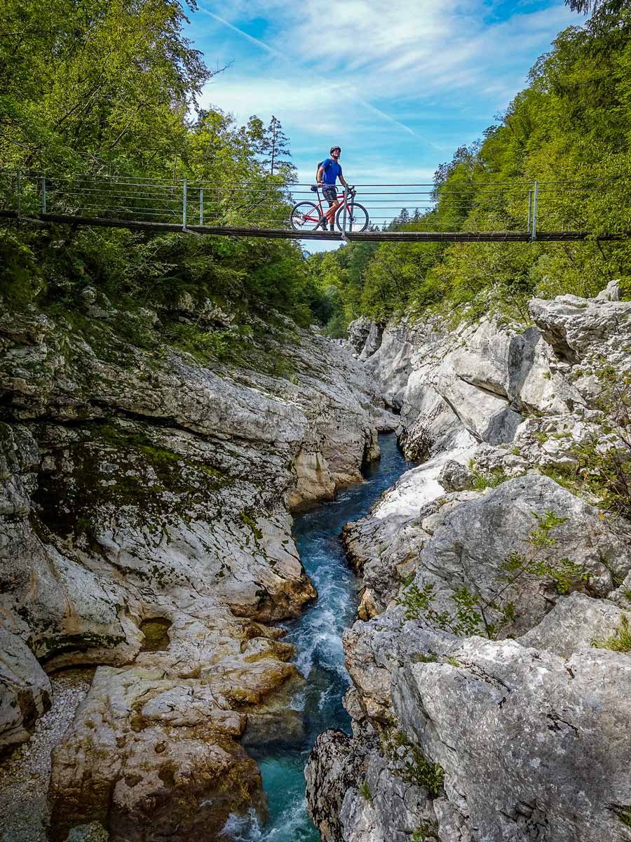 Biker poses on bridge suspended over river gorge in Slovenia