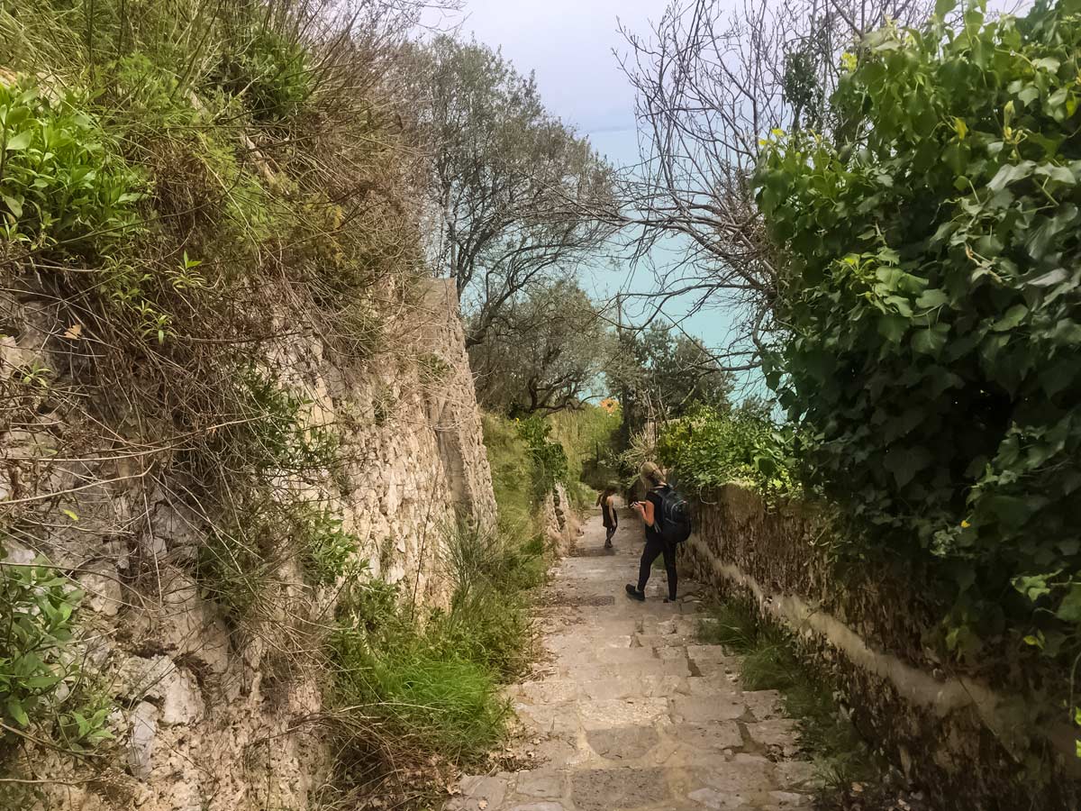 Hikers descend steps toward the sea hiking the Amalfi Coast in Italy