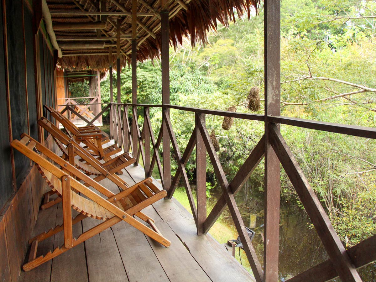 Amazon jungle wooden chairs relaxing on deck camping expedition Peru