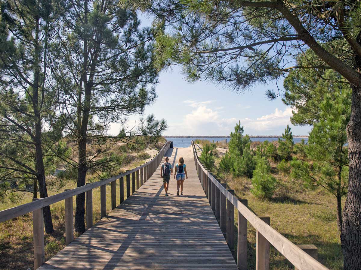 Couple walking to the beach on boardwalk adventure tour Portugal Atlantic coast