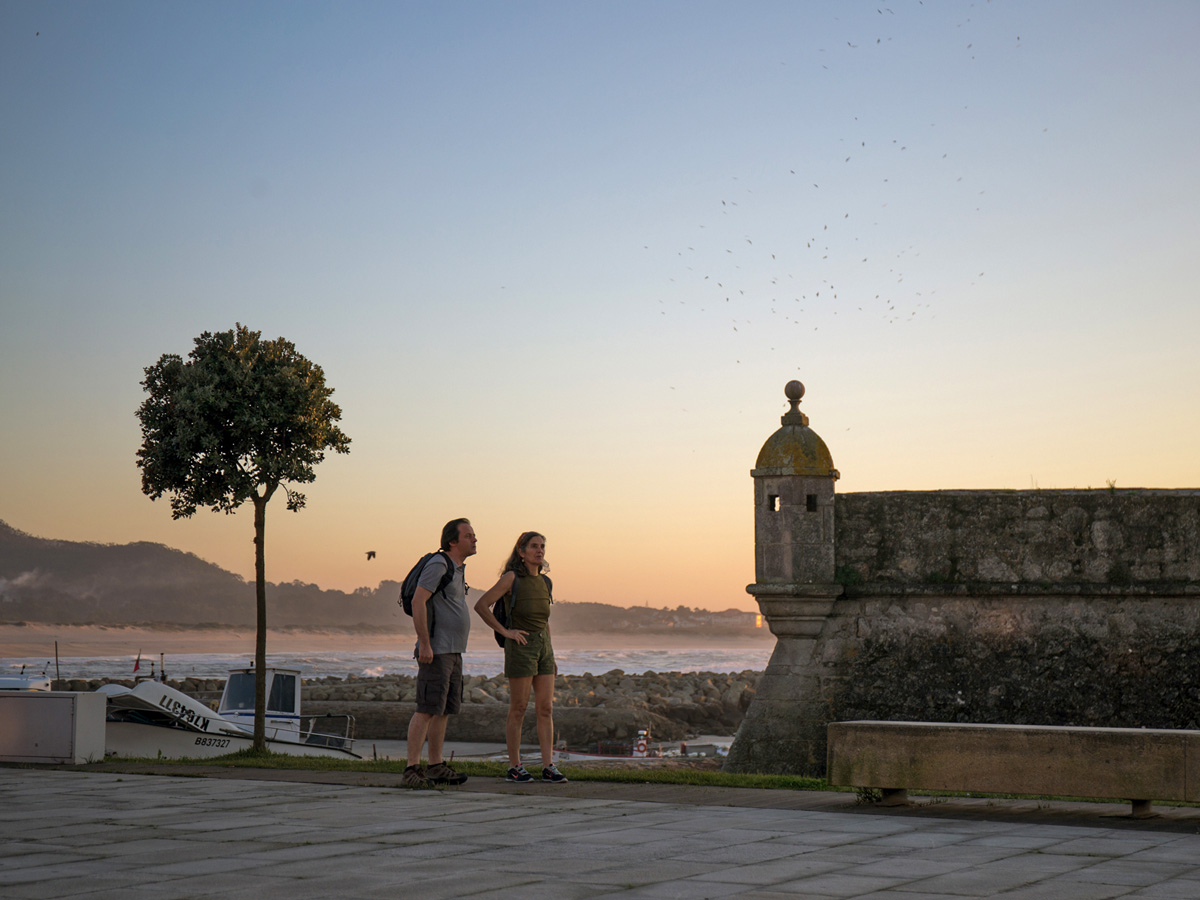 Sunset couple walking by the ocean adventure tour Portugal Atlantic coast
