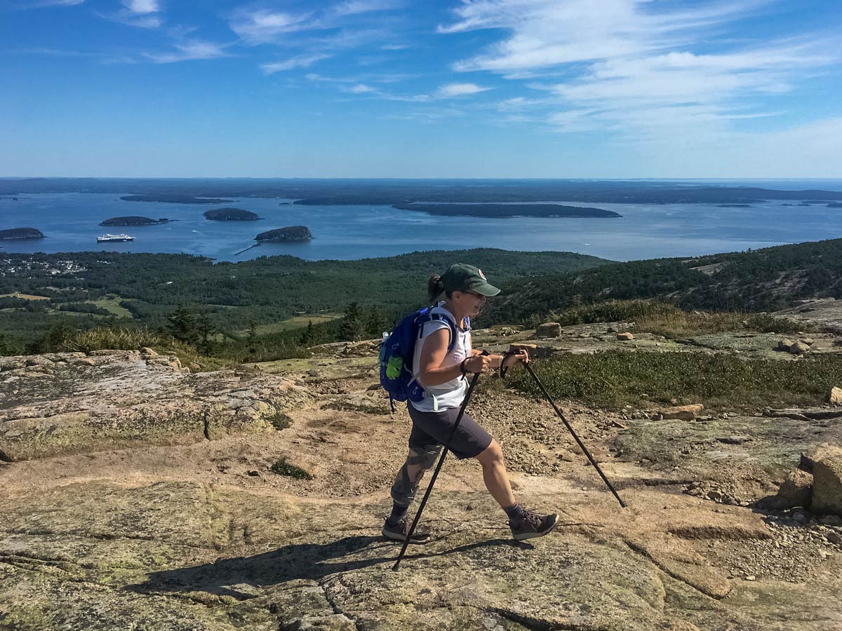Hiker traversing rocks Acadia National Park Maine adventure tour