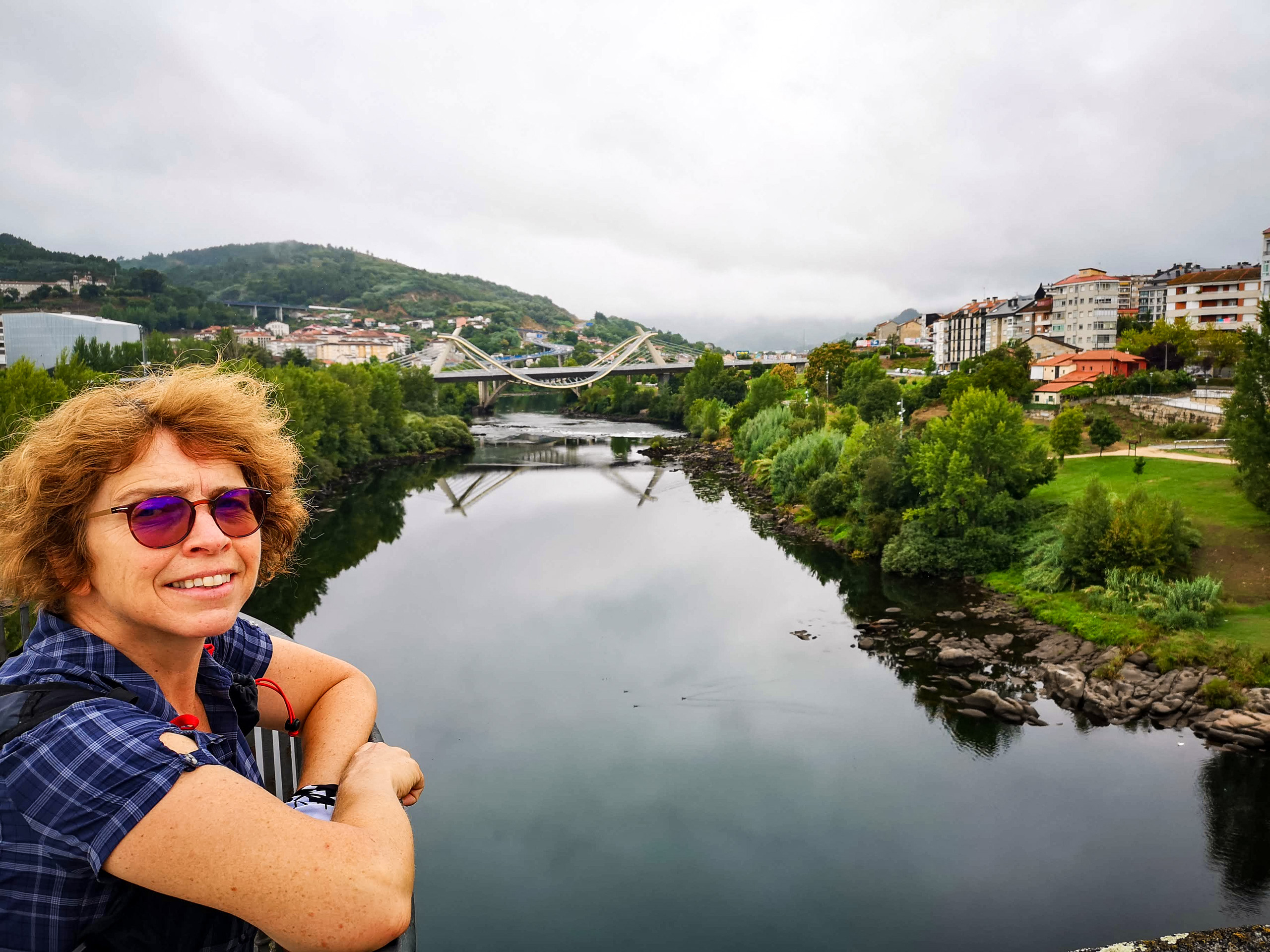 Standing on bridge over clam river arcitectural bridge city hills in the background Camino Sanabres Spain
