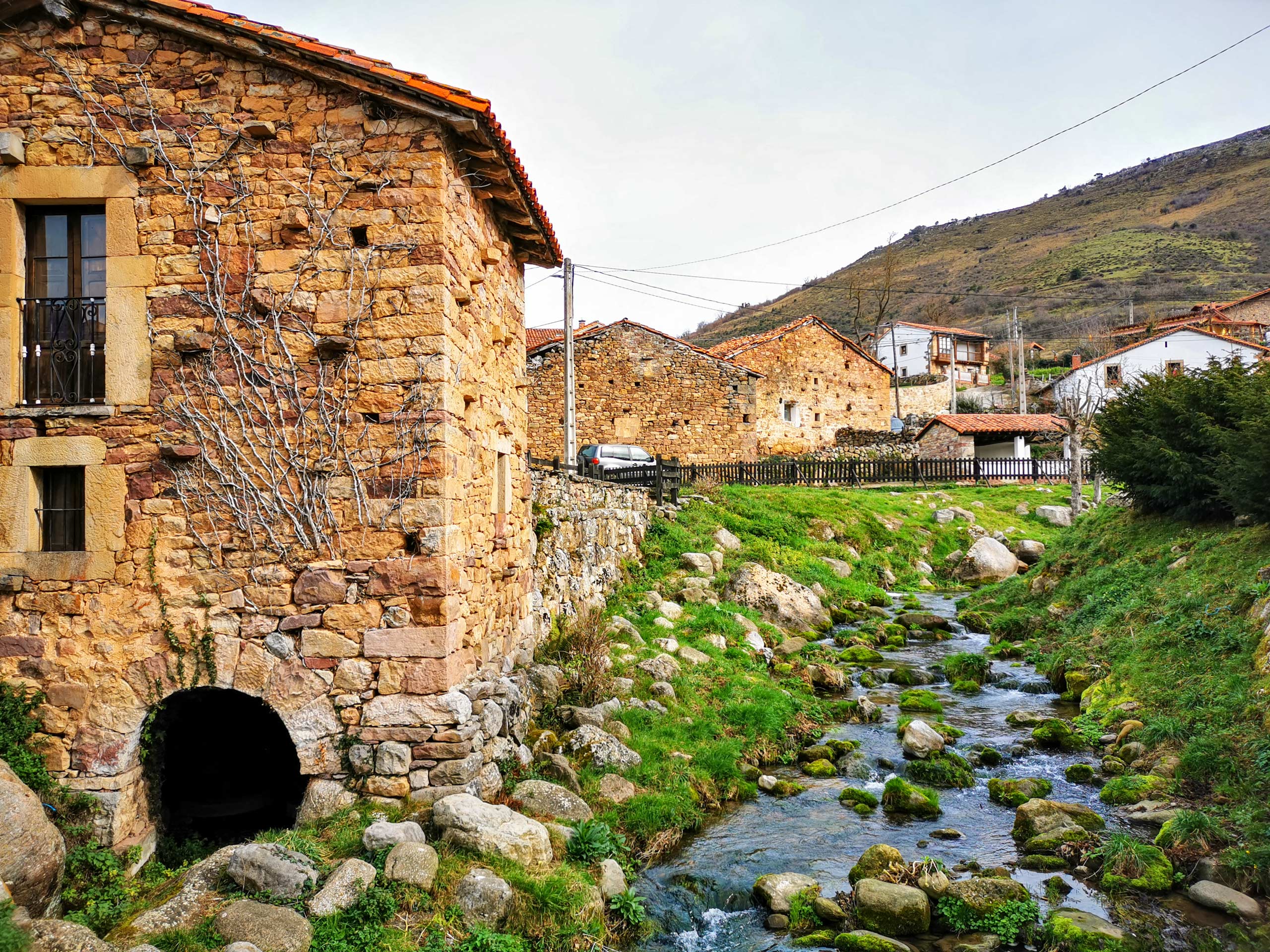 Camino Lebaniego creek running through farming village of stone houses hiking walking tour Spain